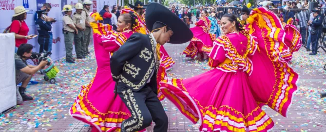 Mexican people dancing in colorful outfits.